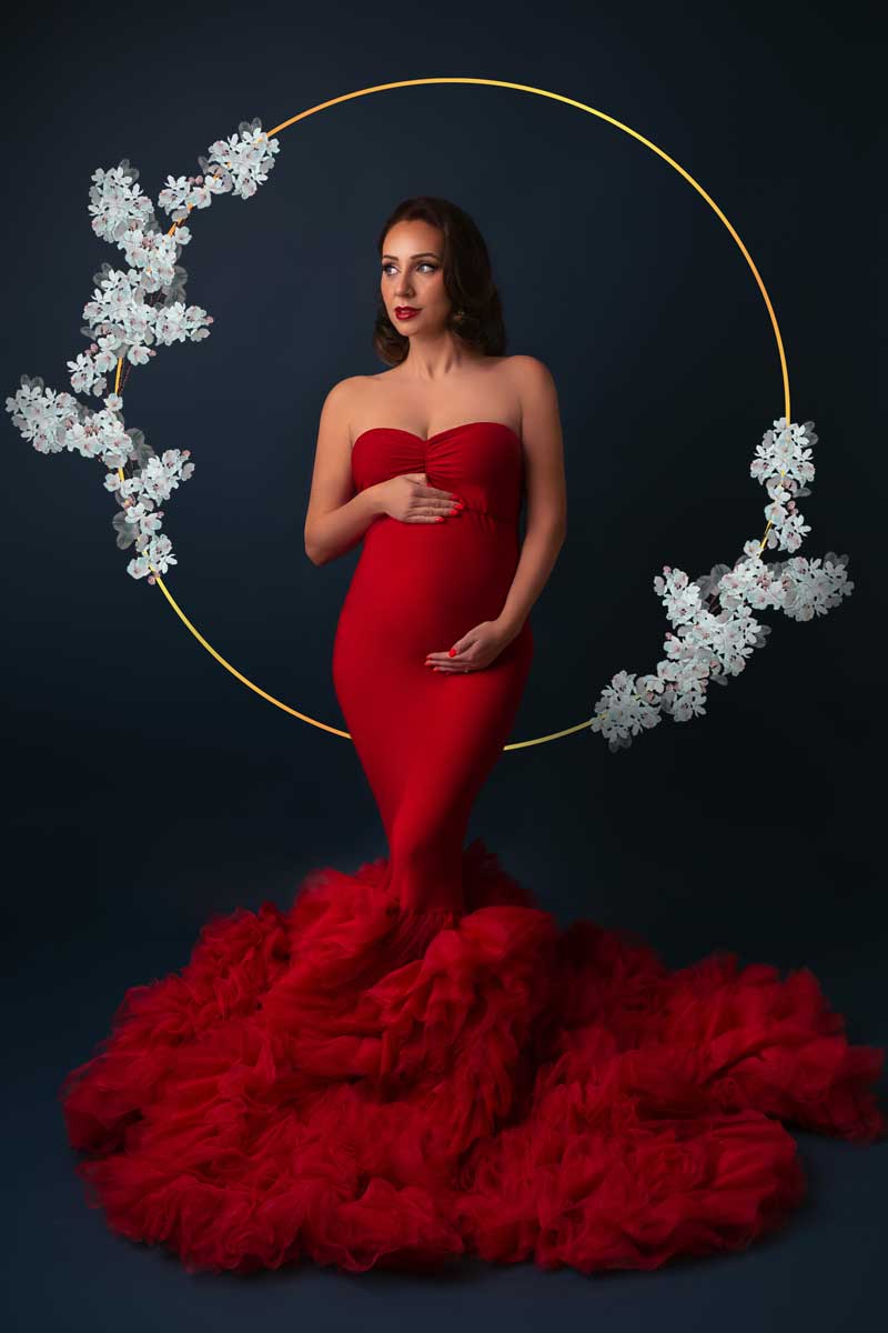 Schwangerschaftsfotografie-in-Muenchen-Elegante-werdende-Mutter-in-rotem-Kleid-und-blauem-Dekor-mit-Blumenkrone